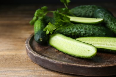 Photo of Fresh ripe cucumbers and parsley on wooden table, closeup