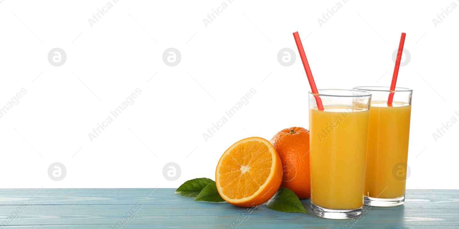 Photo of Delicious orange juice and fresh fruits on light blue wooden table against white background. Space for text