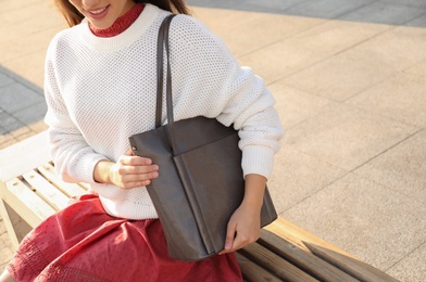 Woman with stylish shopper bag on bench outdoors, closeup