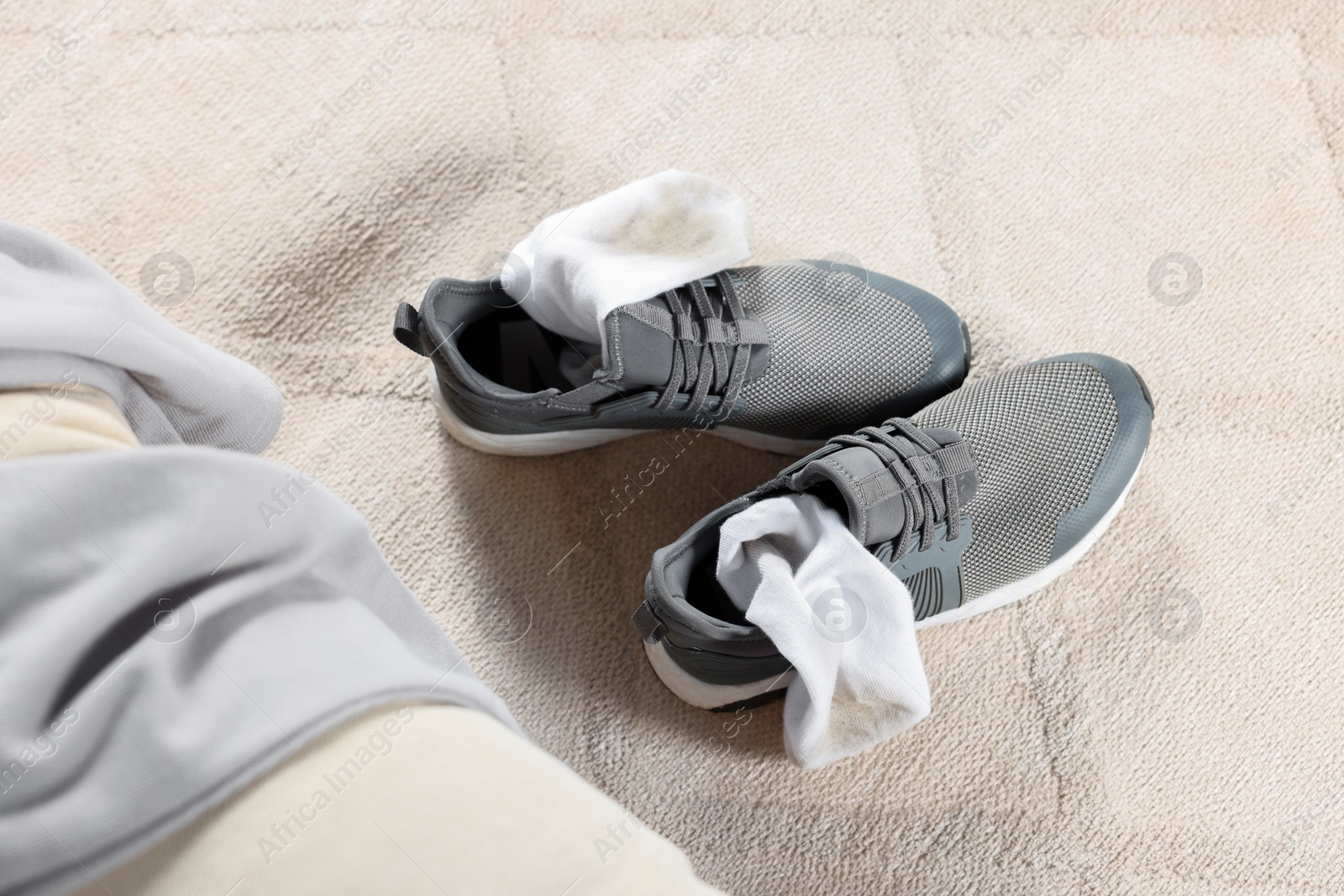 Photo of Sneakers with dirty socks on light carpet indoors