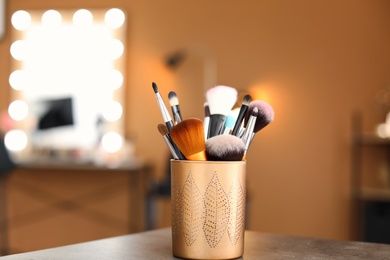 Holder with makeup brushes on table