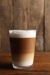 Photo of Glass of delicious layered coffee on wooden table, space for text