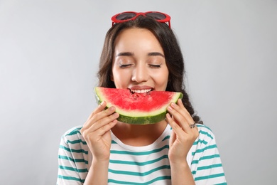 Photo of Beautiful young woman eating watermelon on grey background