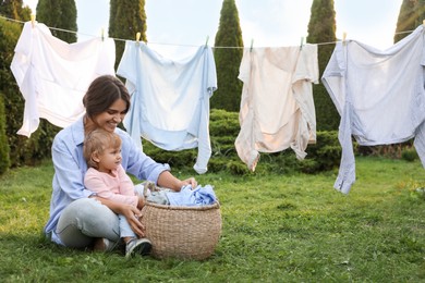 Mother and daughter near washing line with drying clothes in backyard