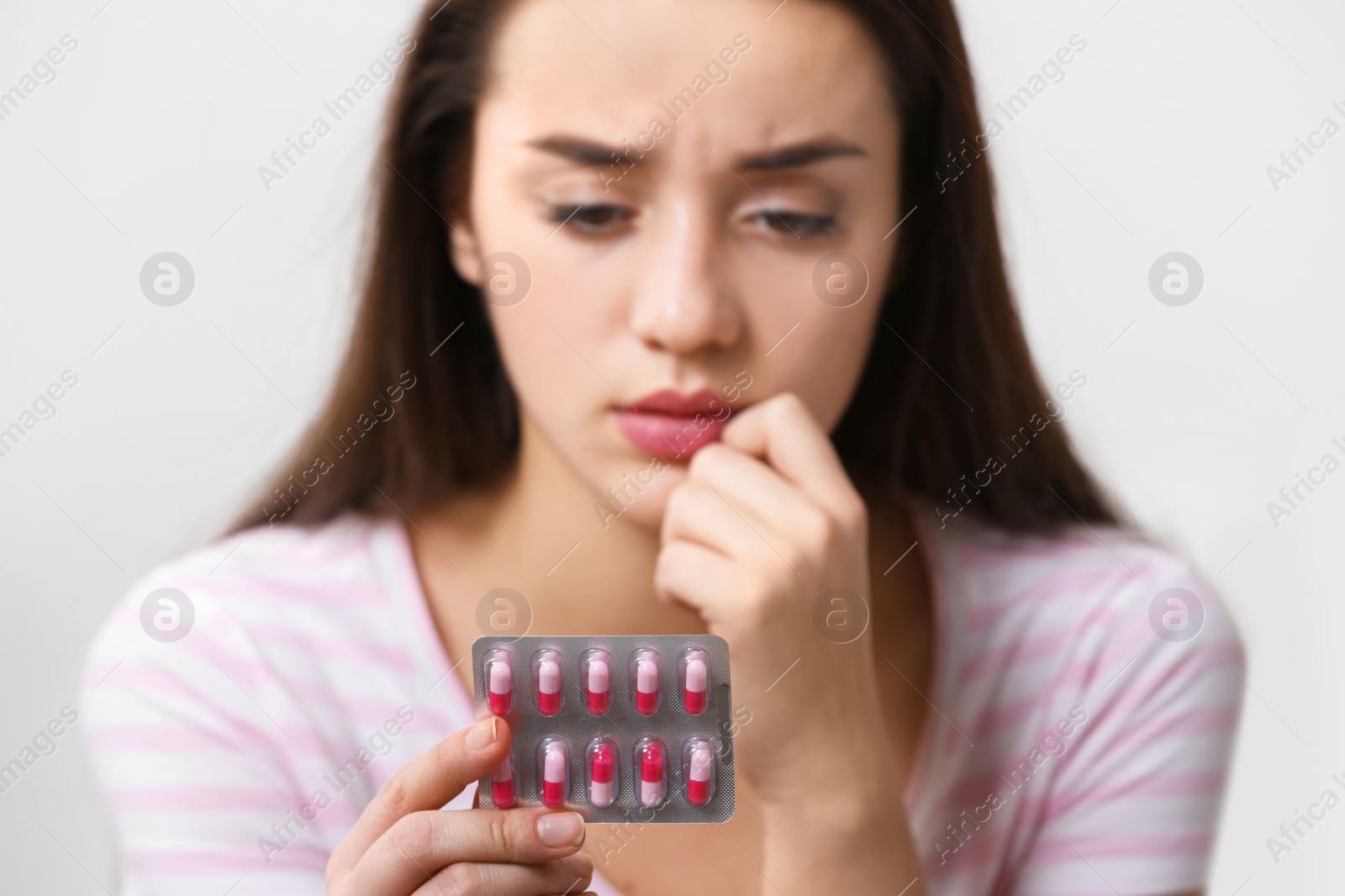 Photo of Young woman with pills on light background, closeup