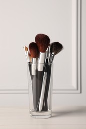Photo of Set of professional makeup brushes on table against white background