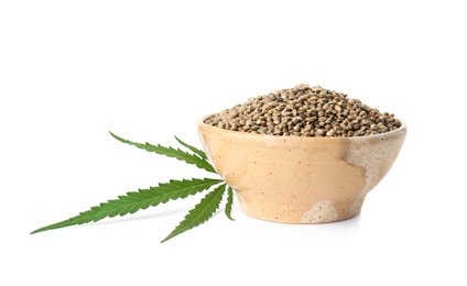 Bowl of hemp seeds with green leaf on white background