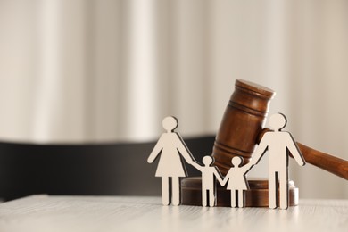 Photo of Law concept. Gavel and figures of parents with children on white wooden table, space for text