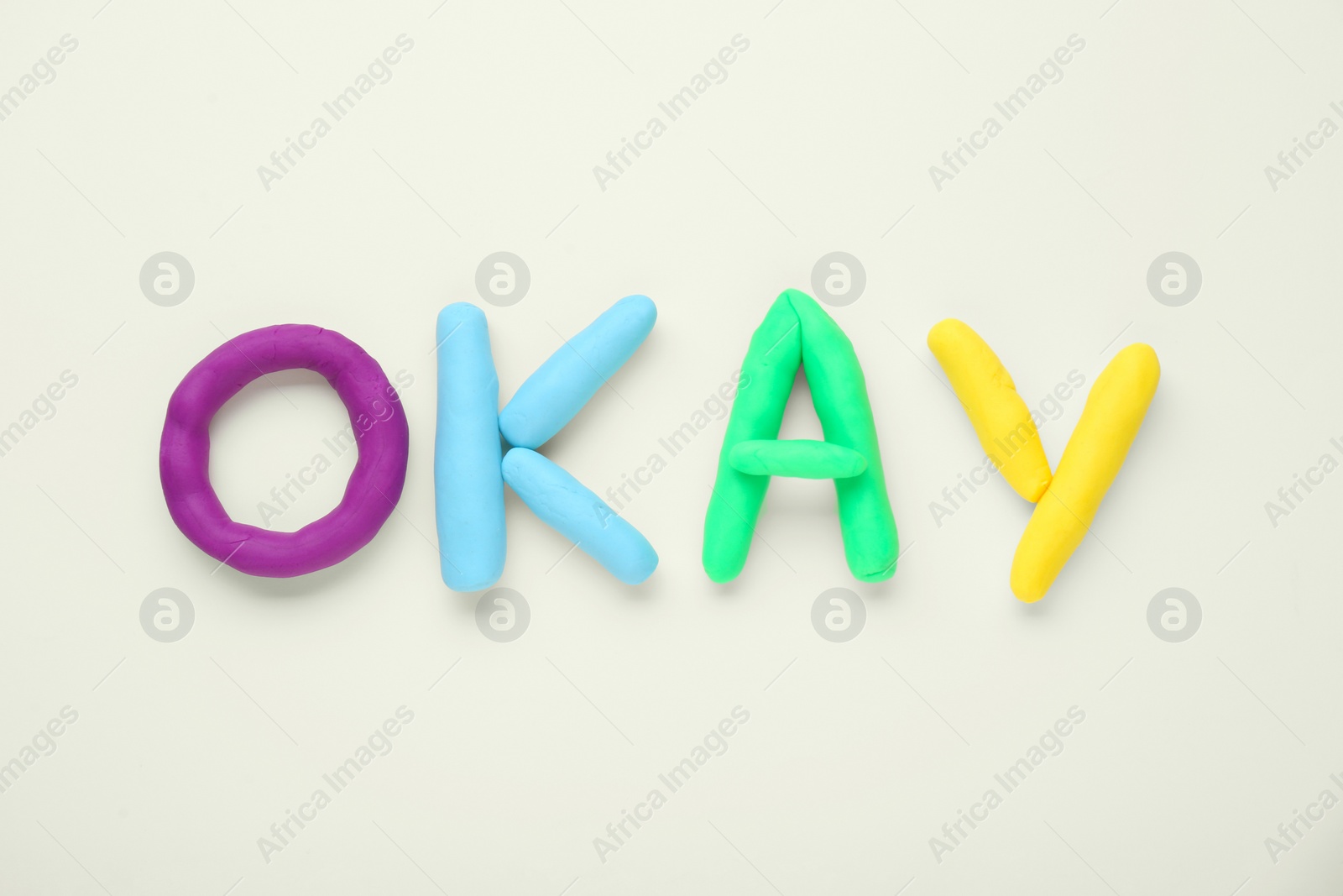 Photo of Word Okay made of colorful plasticine on white background, top view