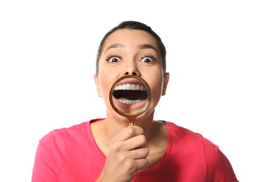 Young woman with healthy teeth and magnifier on white background