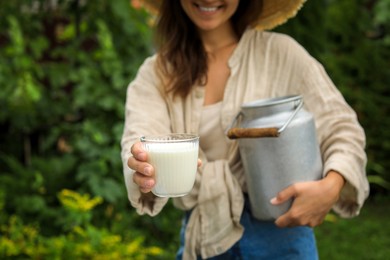 Photo of Smiling woman holding can and glass with fresh milk, closeup