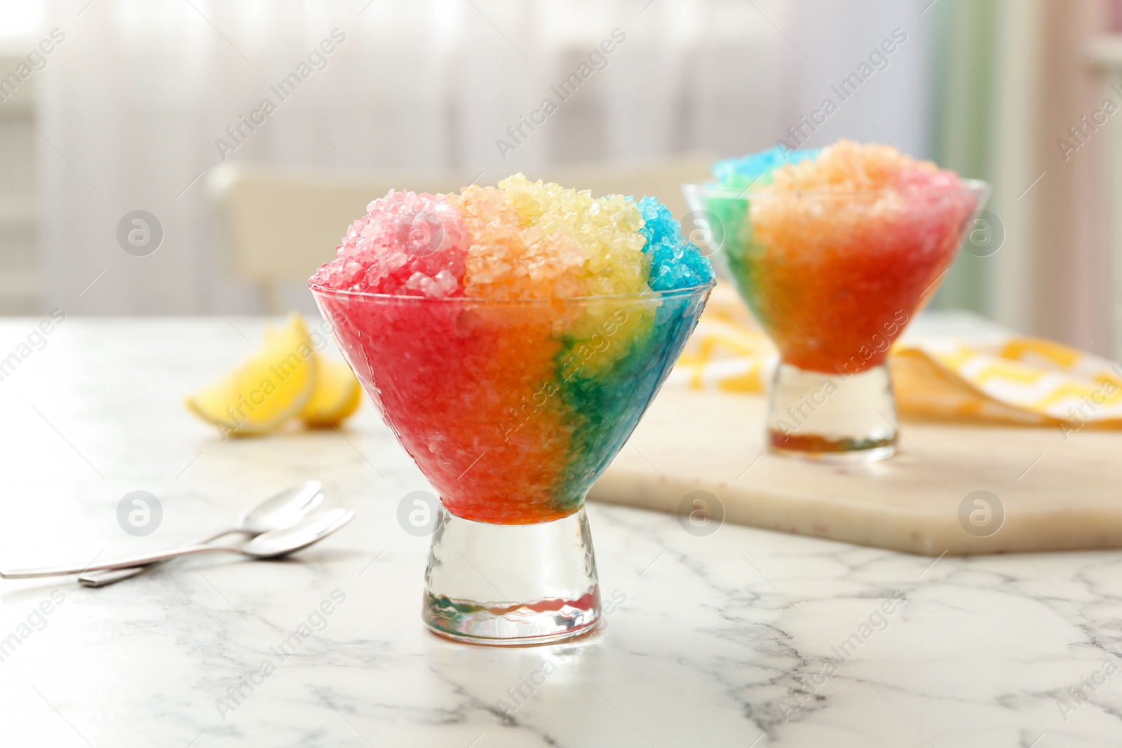 Photo of Rainbow shaving ice in glass dessert bowls on white marble table indoors, closeup