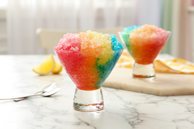 Photo of Rainbow shaving ice in glass dessert bowls on white marble table indoors, closeup