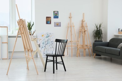 Photo of Studio with easels, chair and sofa. Artist`s workspace