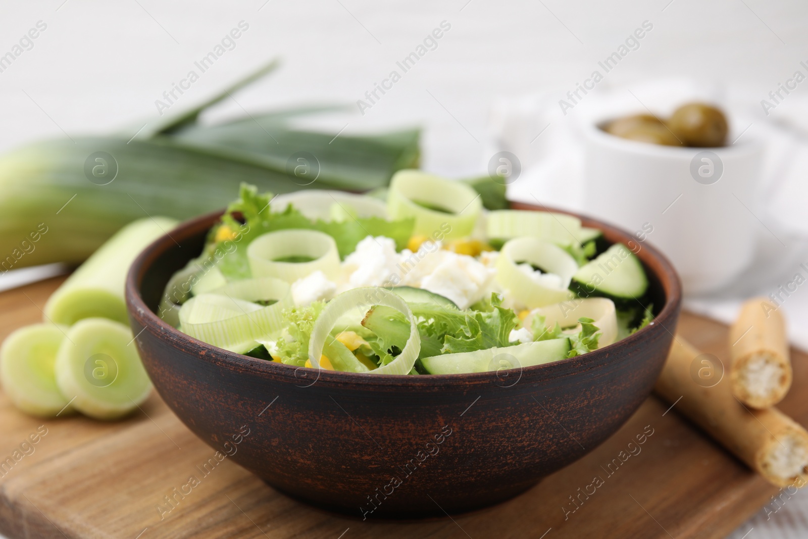 Photo of Bowl of tasty salad with leek and cheese on table, closeup