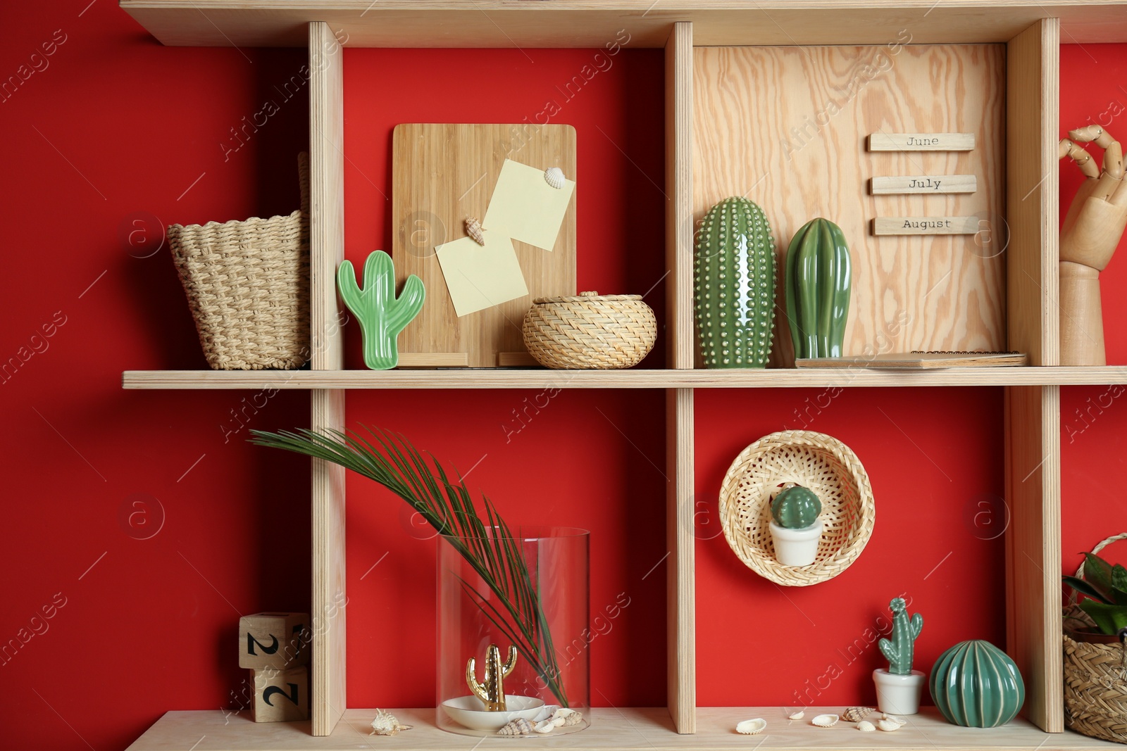 Photo of Stylish wooden shelves with decorative elements on red wall