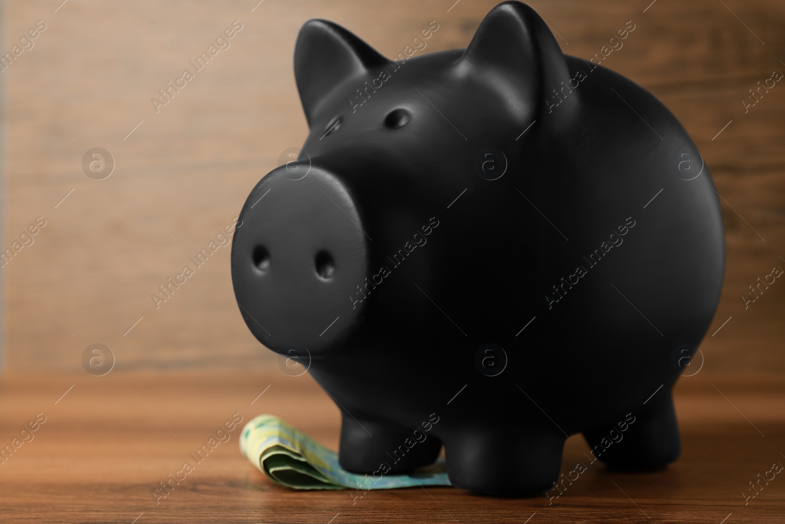 Photo of Ceramic piggy bank and banknotes on wooden table, closeup