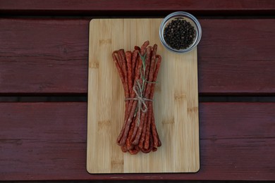 Photo of Tasty dry cured sausages (kabanosy) and spices on wooden table, top view