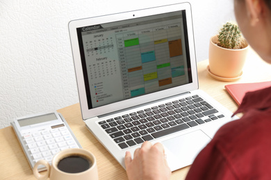 Woman using calendar app on laptop in office, closeup