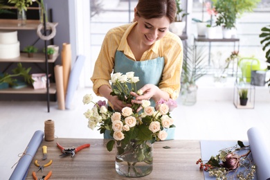 Photo of Female florist creating floral composition at workplace
