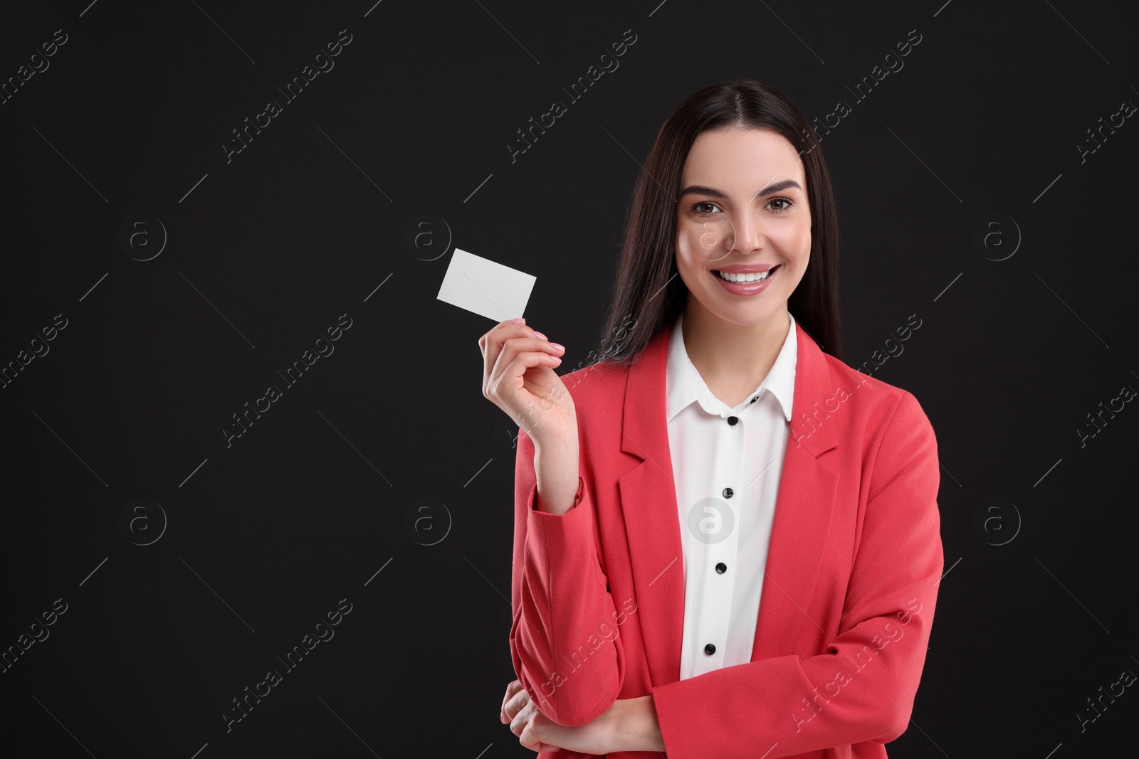 Photo of Happy woman holding blank business card on black background. Space for text