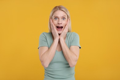 Portrait of surprised woman on yellow background