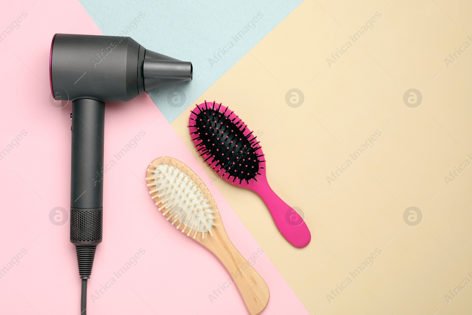 Photo of Hair dryer and different brushes on color background, flat lay. Professional hairdresser tool
