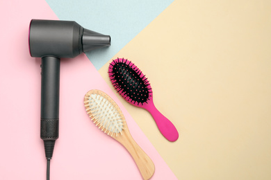 Hair dryer and different brushes on color background, flat lay. Professional hairdresser tool