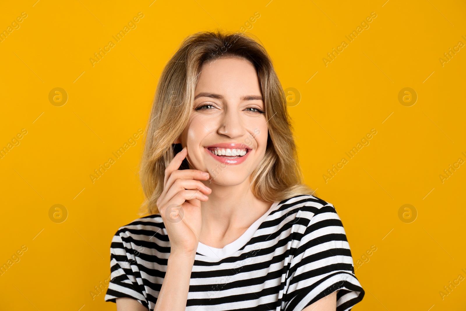 Photo of Portrait of happy young woman with beautiful blonde hair and charming smile on yellow background