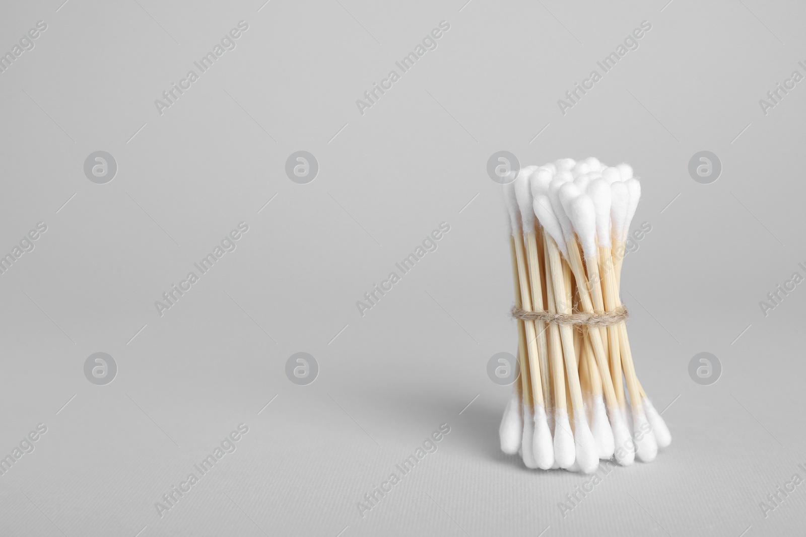 Photo of Bunch of wooden cotton buds on light grey background. Space for text