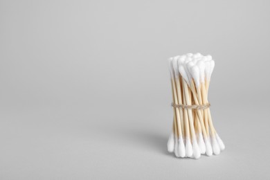 Photo of Bunch of wooden cotton buds on light grey background. Space for text