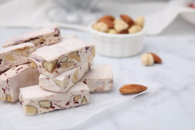 Photo of Pieces of delicious nutty nougat on white table, closeup