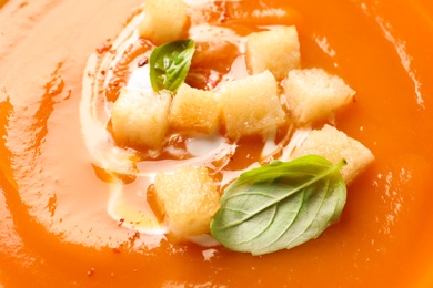 Sweet potato soup with croutons and basil as background, closeup