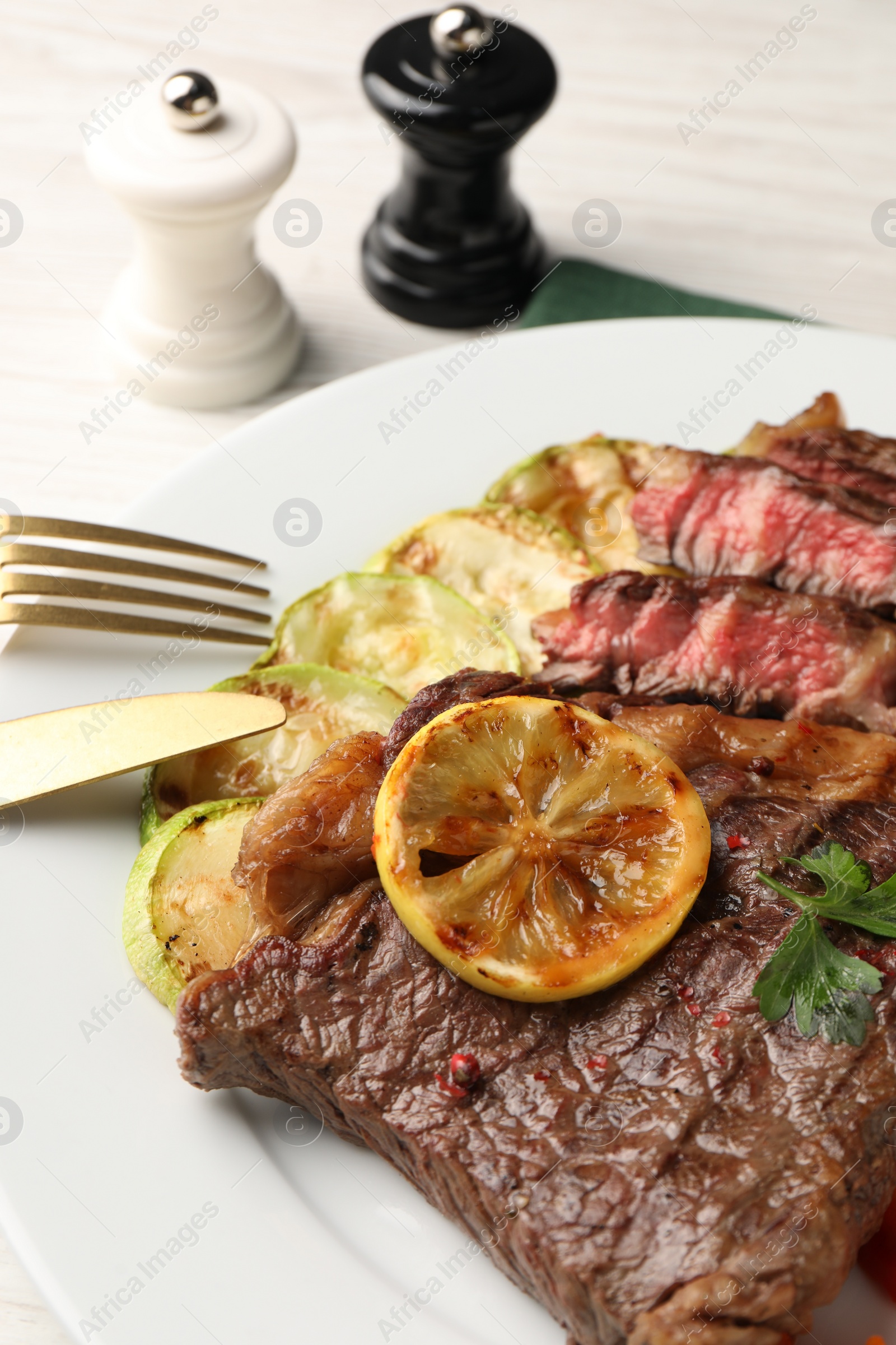 Photo of Delicious grilled beef steak and zucchini on plate, closeup