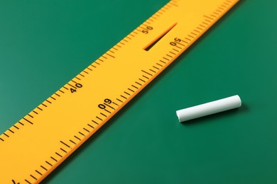 Photo of Ruler and chalk on green chalkboard, closeup