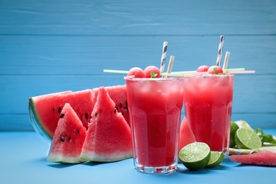 Photo of Tasty watermelon drink and fresh fruits on light blue background