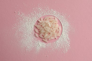 Loose face powder and rice on pink background, top view