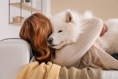 Photo of Woman with her dog lying on sofa at home