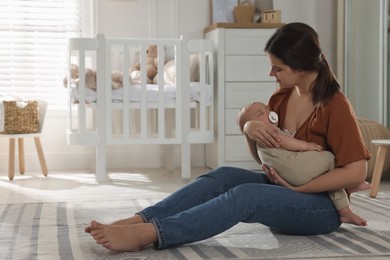 Photo of Happy young mother with her sleeping baby in nursery. Space for text