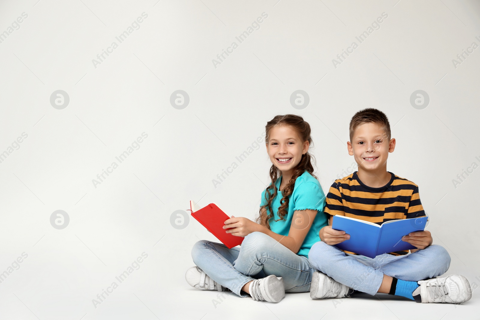 Photo of Little children reading books on grey background. Space for text