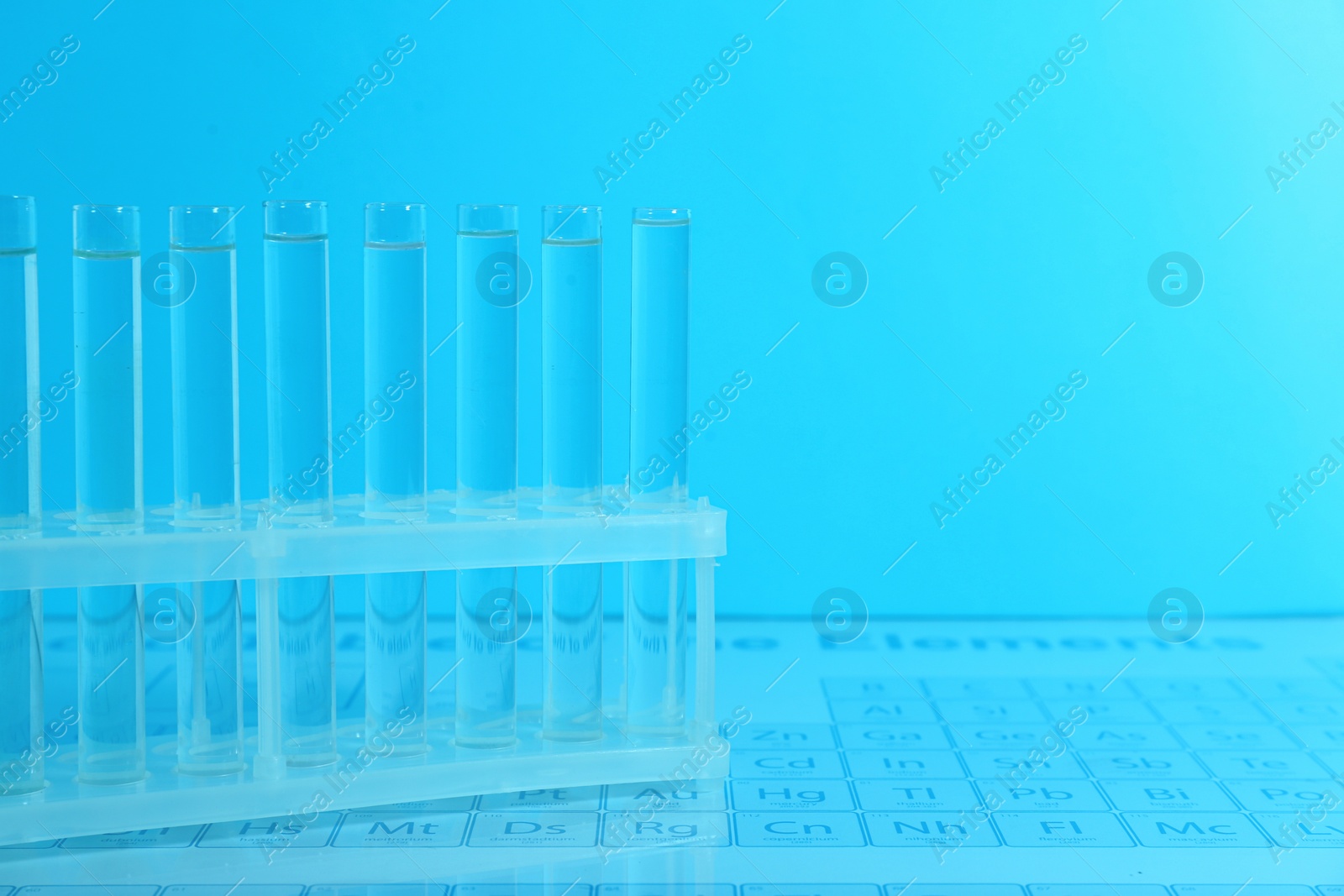 Photo of Test tubes on periodic table of elements, toned in light blue. Space for text