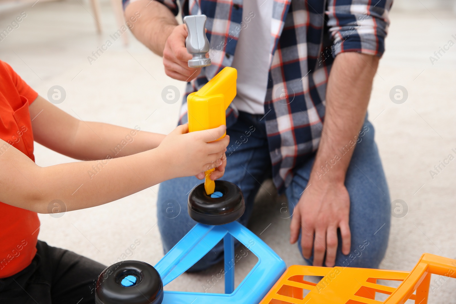 Photo of Man and his child as repairman playing with toy cart at home, closeup