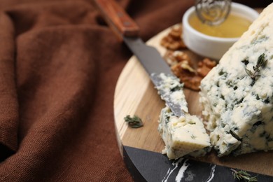 Tasty blue cheese with thyme and knife on wooden board, closeup. Space for text