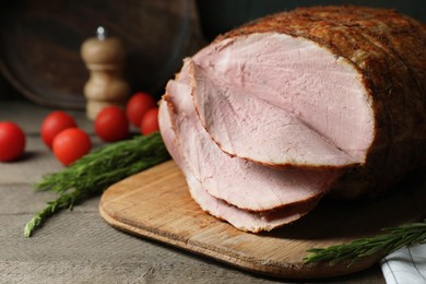Photo of Delicious baked ham, tomatoes and rosemary on grey wooden table, closeup