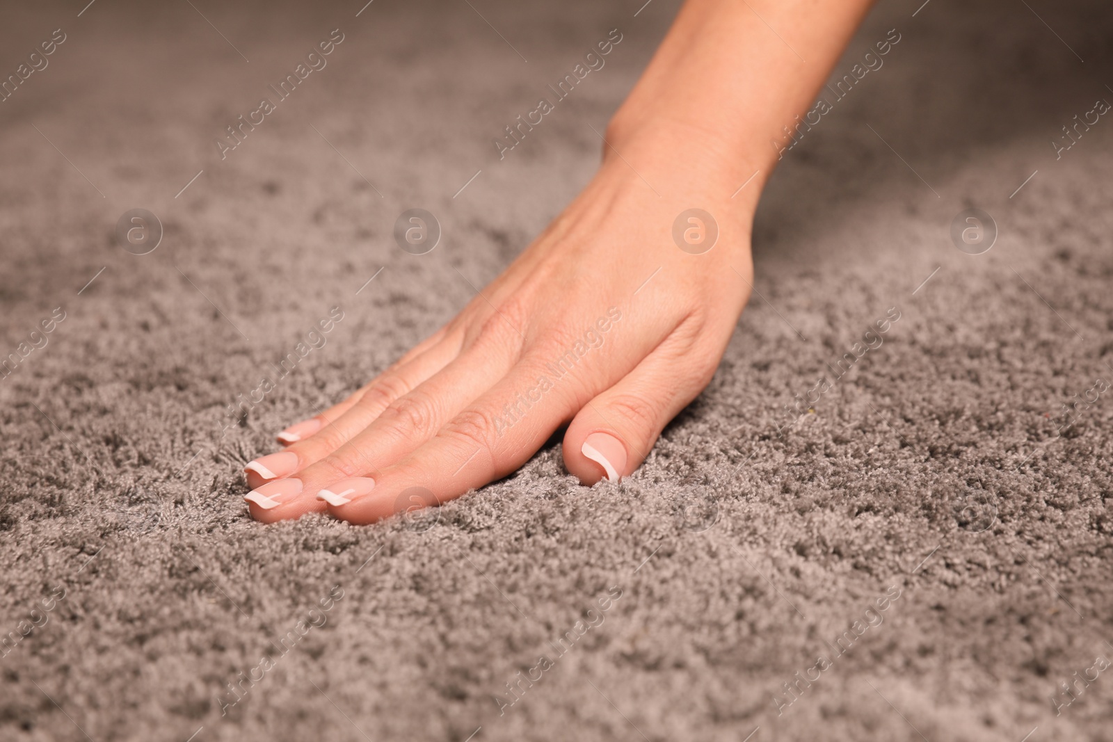 Photo of Woman touching soft grey carpet fabric, closeup