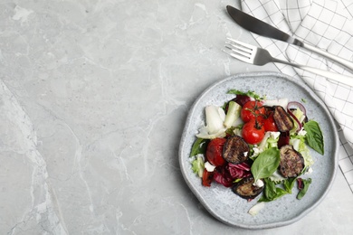 Photo of Delicious salad with roasted eggplant, basil and cheese served on grey marble table, flat lay. Space for text