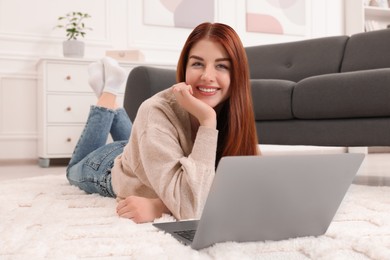Photo of Beautiful woman with laptop on rug in living room