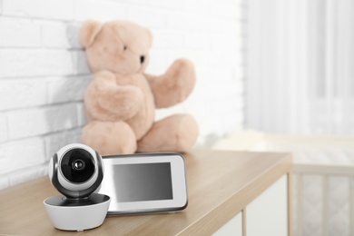 Photo of Baby monitor with camera and toy on chest of drawers in room, space for text. Video nanny