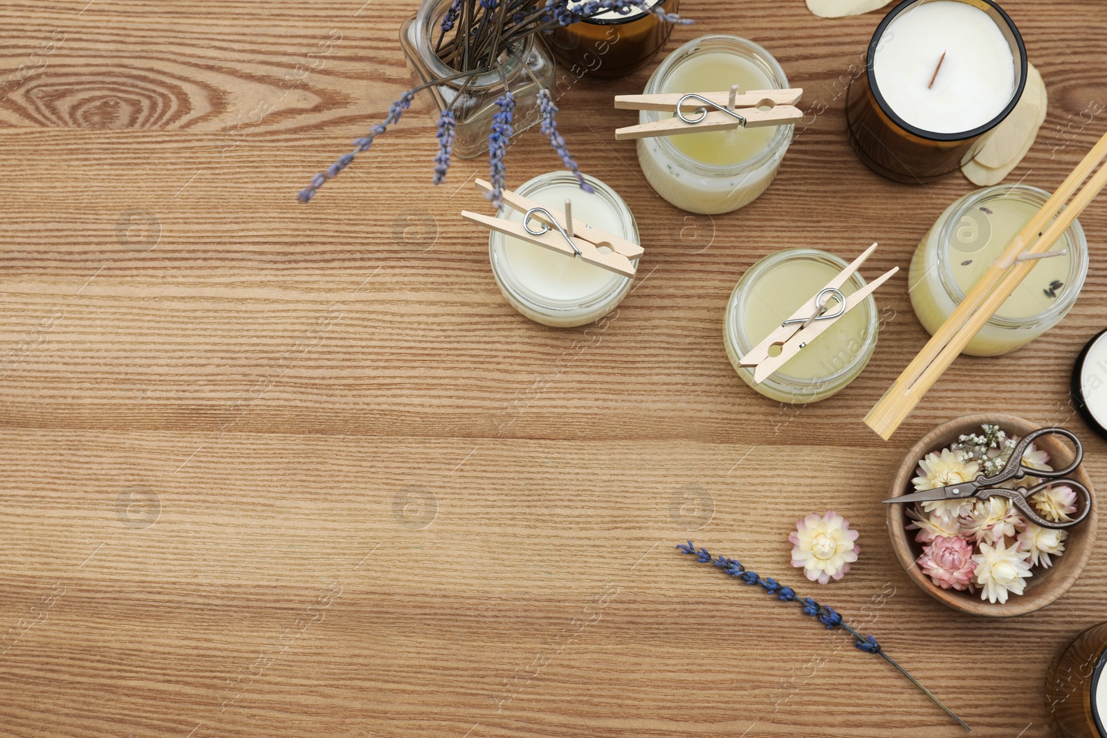 Photo of Glass jars with wax and space for text on wooden table, flat lay. Handmade candle