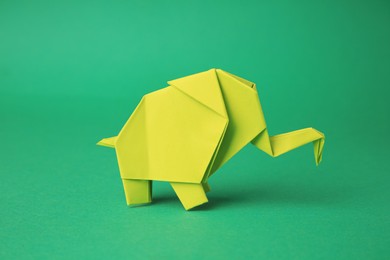 Origami art. Paper elephant on green background